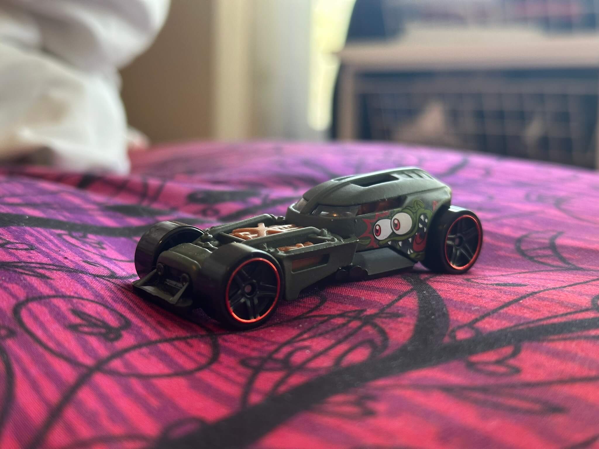 Dragster Hot Wheels sitting on a pink bedsheet