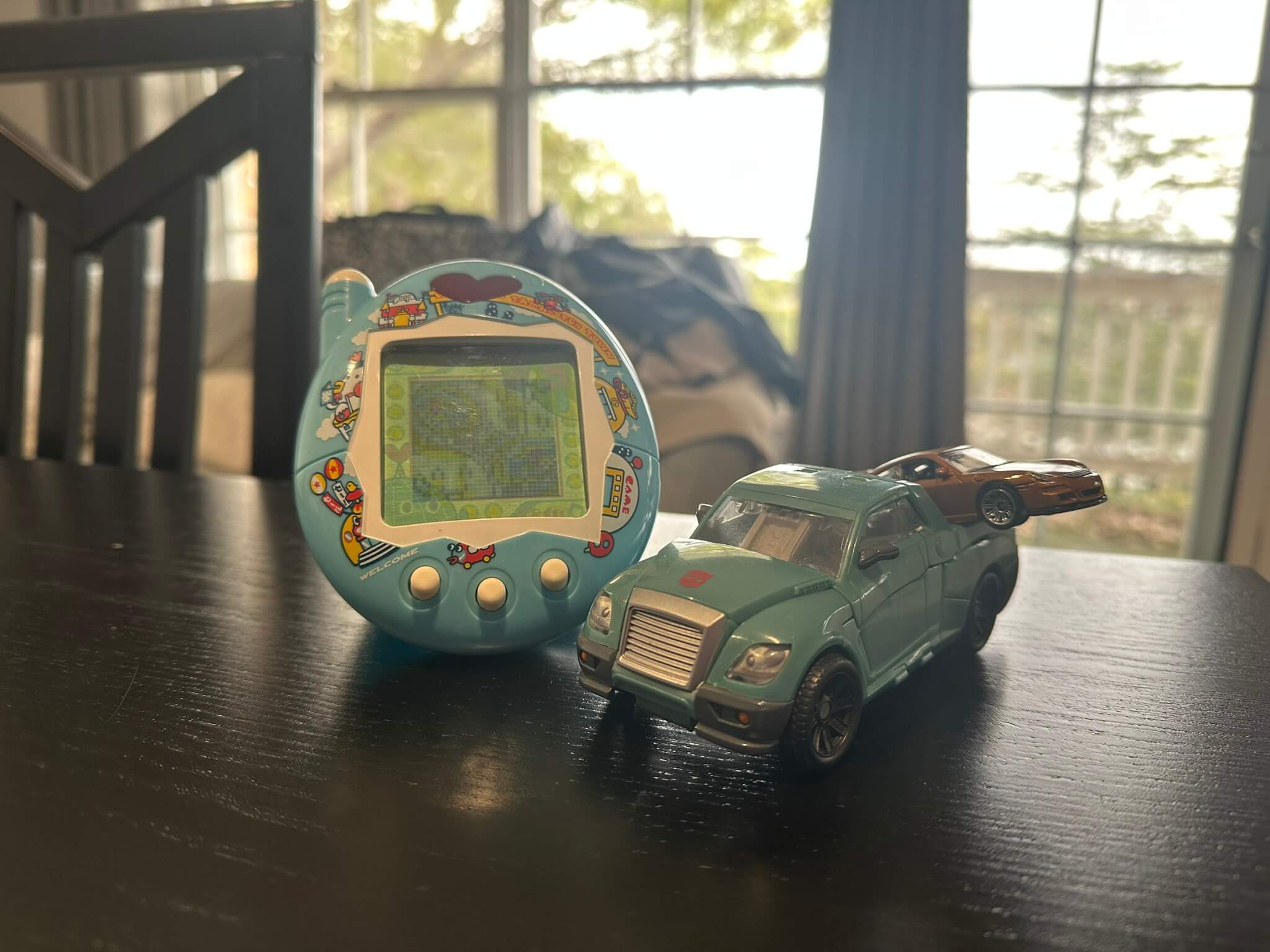 Large blue Tamagotchi, green pickup Transformer carrying a brown Hot Wheels in its bed