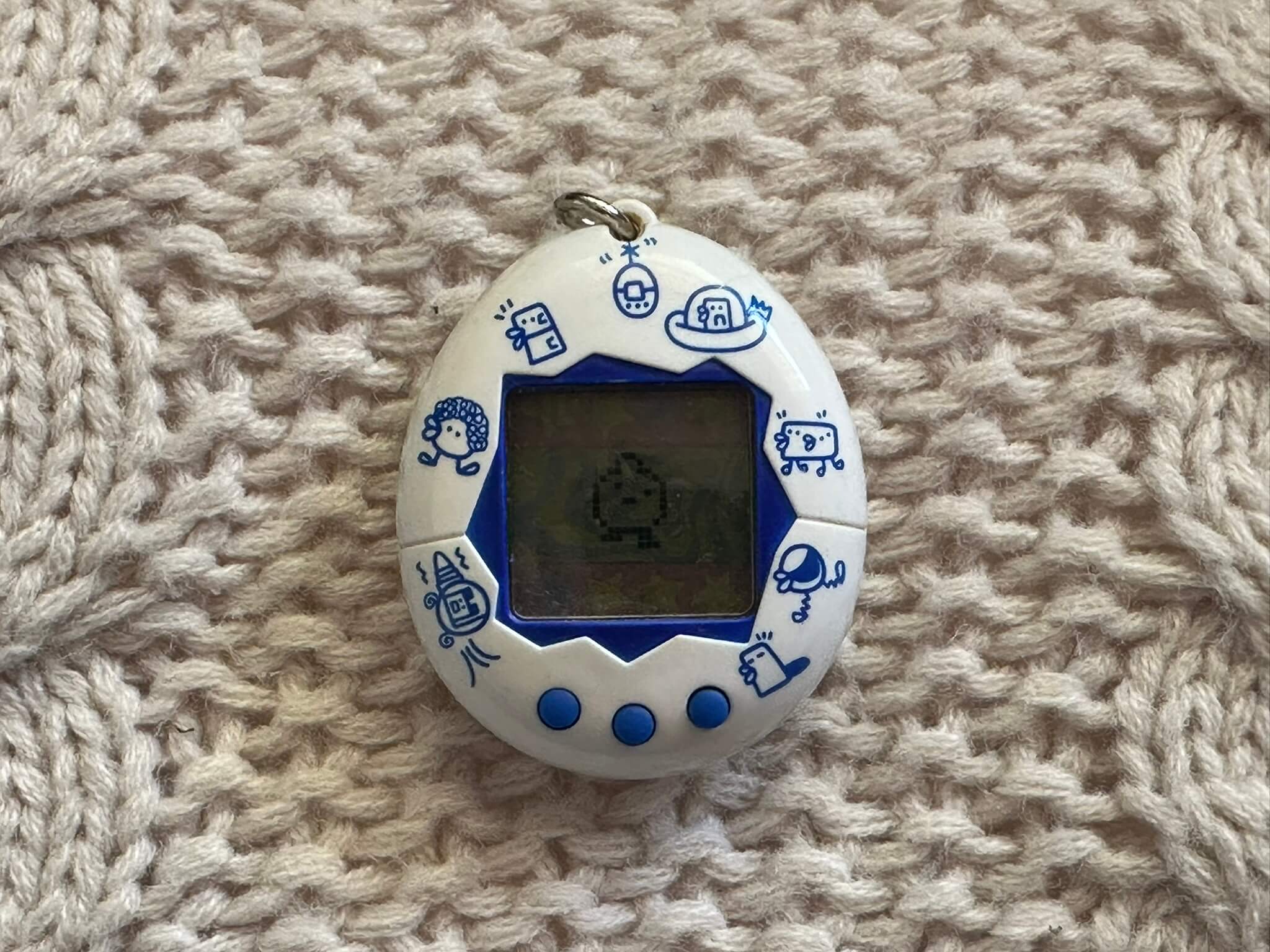 White Tamagotchi on a woven background